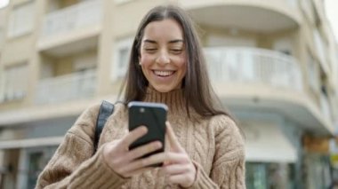 Sokakta gülümseyen akıllı telefon kullanan genç, güzel İspanyol kadın.