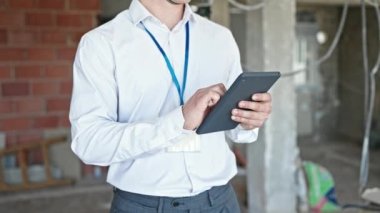 Şantiyedeki dokunmatik dokuyu kullanarak rahat bir ifadeyle duran genç İspanyol mimar.