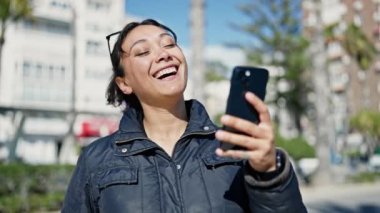 Sokakta gülümseyen akıllı telefon kullanan genç, güzel İspanyol kadın.