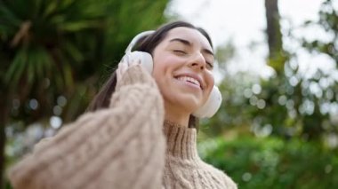 Genç, güzel İspanyol kadın parkta müzik dinliyor ve dans ediyor.