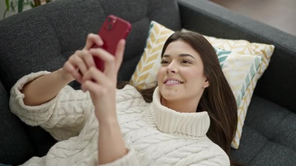 Evdeki Kanepede Uzanmış Akıllı Telefon Kullanan Genç Güzel Spanyol Kadın — Stok video