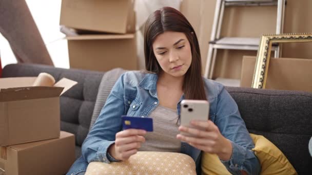 新しい家でスマートフォンやクレジットカードで若い美しいヒスパニック系女性のショッピング — ストック動画