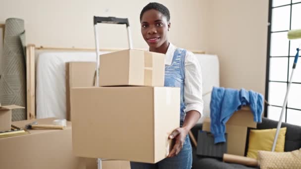 アフリカ系アメリカ人女性が自信を持って新しい家で包装を保持笑顔 — ストック動画