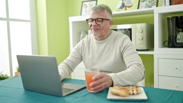 Mężczyzna Średnim Wieku Siwowłosy Jedzący Śniadanie Przy Użyciu Laptopa Domu — Wideo stockowe