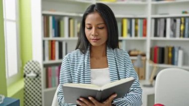 African american woman student reading book doing silence gesture at library university