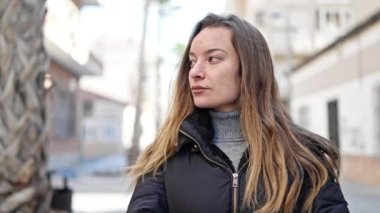 Young caucasian woman standing with serious expression at street