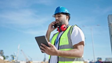 Afro-Amerikalı inşaatçı akıllı telefondan konuşuyor.