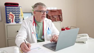 Klinikte çalışırken orta yaşlı, gri saçlı bir doktor.