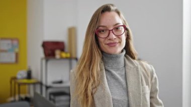 Kafkasyalı genç bir iş kadını ofiste kendinden emin gülümsüyor.