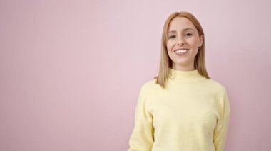 Young blonde woman smiling confident pointing with finger to the side over isolated pink background