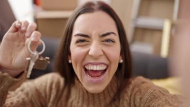 Genç, güzel, İspanyol bir kadın anahtarlarını tutuyor ve yeni evinde video görüşmesi yapıyor.