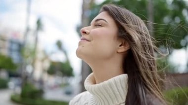 Young beautiful hispanic woman breathing with closed eyes at street