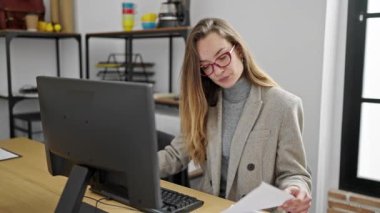 Ofisteki bilgisayar okuma belgesini kullanan beyaz kadın bir iş adamı.