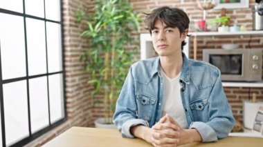 Yemek odasındaki masada kendinden emin gülümseyen İspanyol genç adam.