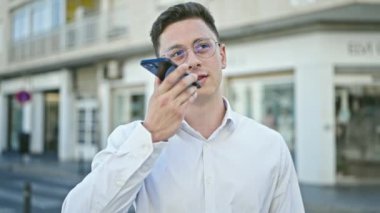 Genç İspanyol adam sokakta akıllı telefonuyla sesli mesaj yolluyor.