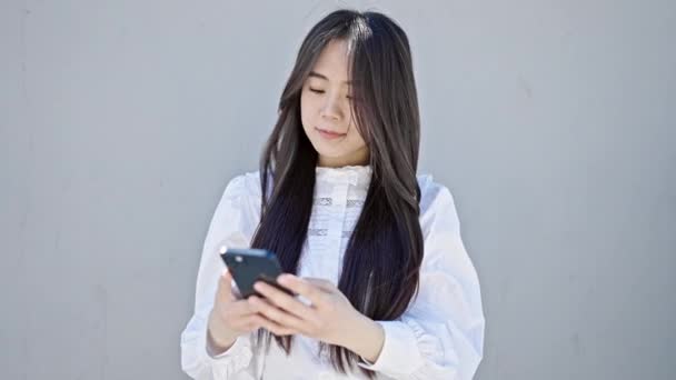 Junge Chinesin Benutzt Smartphone Mit Ernstem Gesichtsausdruck Vor Isoliertem Weißen — Stockvideo