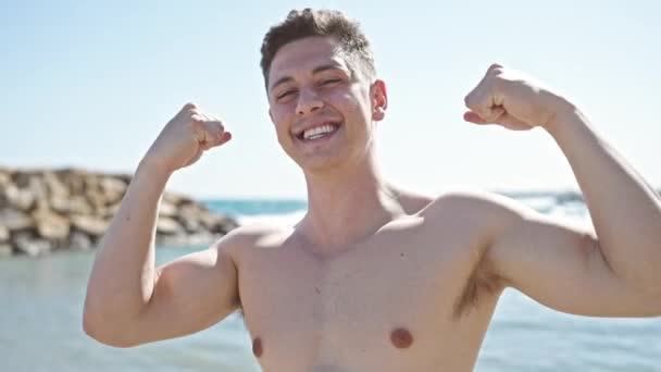 年轻的他的惊慌失措的男人带着自信的笑容在海滨做着获胜的手势 — 图库视频影像