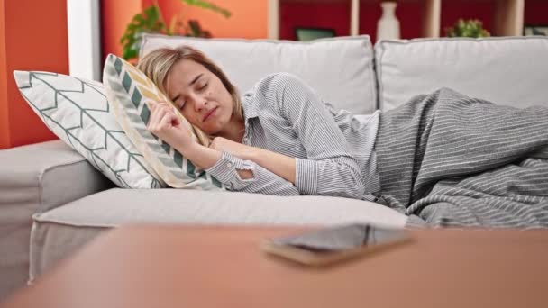 睡在沙发上的金发女人关掉家里的智能手机闹钟 — 图库视频影像