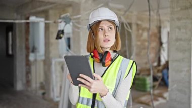 Genç sarışın mimar inşaat alanında ciddi bir ifadeyle dokunmatik ped kullanıyor.