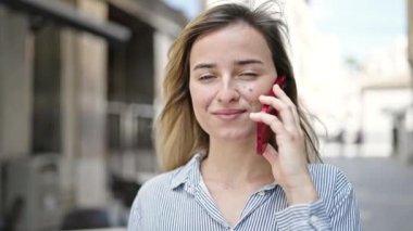 Sokakta akıllı telefon kullanan, kendine güvenen genç sarışın kadın.