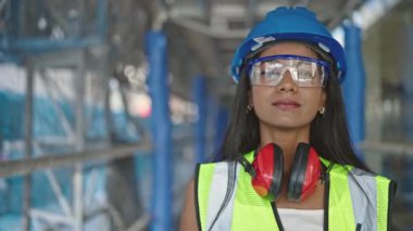 Afro-Amerikalı kadın inşaatçı gülümseyerek sokakta duruyor.