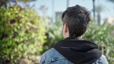 Parkta arkada duran İspanyol genç adam.