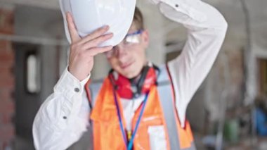 Kafkasyalı genç mimar inşaat alanında kendine güvenen kasketli gülümsüyor.