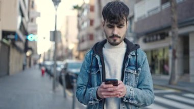 Sokakta akıllı telefon kullanan genç bir İspanyol.