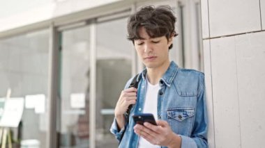 Genç İspanyol öğrenci üniversitede rahat bir ifadeyle akıllı telefon kullanıyor.