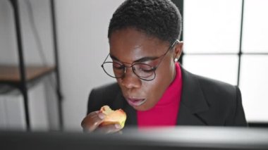 Ofiste elma yiyen Afrikalı Amerikalı iş kadını.