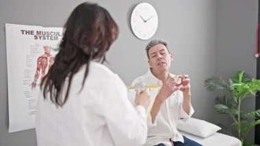 Kıdemli erkek ve kadın doktor ve hasta klinikte muayene raporları yazıyorlar.