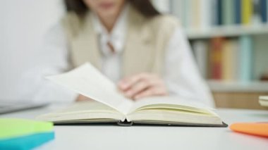 Genç, güzel, İspanyol bir kadın kitap okuyor. Üniversite sınıfının bir sonraki sayfasını çeviriyor.