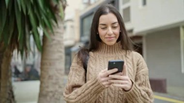 Sokakta gülümseyen akıllı telefon kullanan genç, güzel İspanyol kadın.