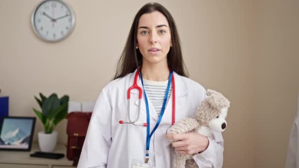 Młoda Piękna Latynoska Lekarz Trzyma Misia Prosząc Ciszę Klinice — Wideo stockowe