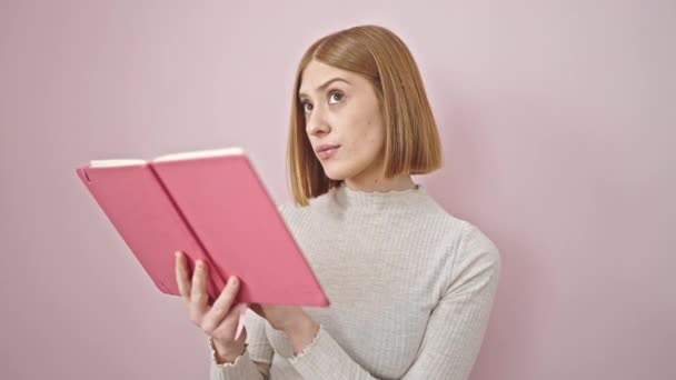 Молода Блондинка Читає Книгу Над Ізольованим Рожевим Тлом — стокове відео