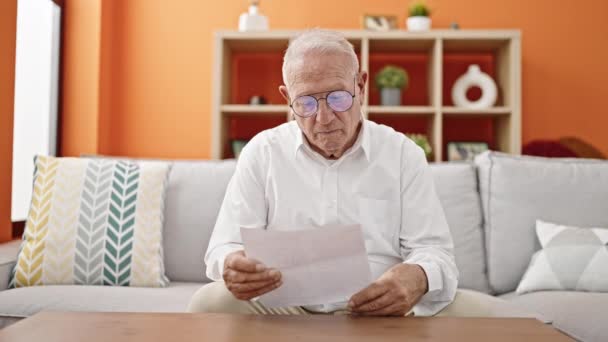 Yaşlı Gri Saçlı Adam Evdeki Kanepede Oturmuş Belge Okuyor — Stok video
