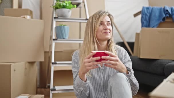 Νεαρή Ξανθιά Γυναίκα Πίνει Καφέ Καθισμένη Στο Πάτωμα Του Νέου — Αρχείο Βίντεο