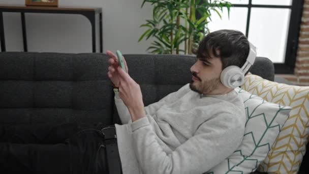 Jonge Spaanse Man Met Behulp Van Smartphone Liggend Bank Luisteren — Stockvideo