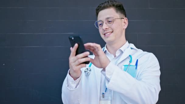 Jovem Hispânico Homem Médico Sorrindo Confiante Usando Smartphone Sobre Fundo — Vídeo de Stock