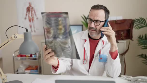 Чоловік Середнього Віку Лікар Розмовляє Смартфоні Дивлячись Рентген Клініці — стокове відео