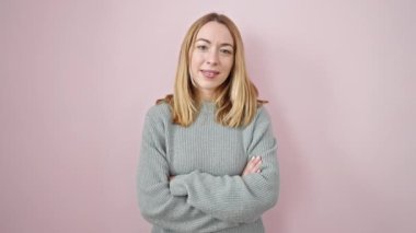 Young blonde woman standing with surprise expression over isolated pink background