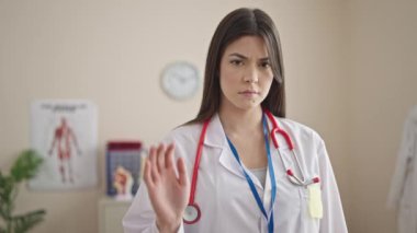 Genç, güzel İspanyol kadın doktor klinikte el hareketlerini durduruyor.