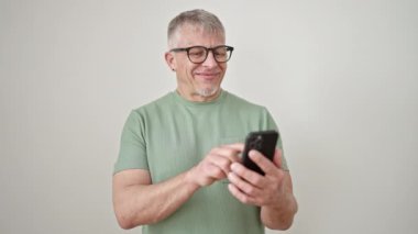Orta yaşlı, gri saçlı, kendine güvenen, izole beyaz arka plan üzerinde akıllı telefon kullanan bir adam.
