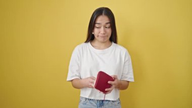Genç, güzel İspanyol kadın izole edilmiş sarı arka planda boş cüzdan gösteriyor.