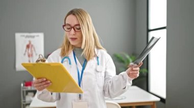 Genç sarışın kadın doktor klinikte röntgen raporu okuyor.