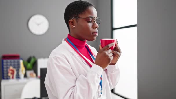 African American Woman Doctor Smelling Cup Coffee Clinic — Stock Video