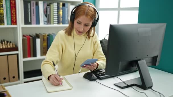 Young Blonde Woman Student Using Smartphone Writing Notebook University Classroom — Vídeos de Stock