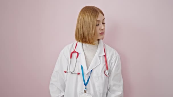 年轻的金发女医生要求对孤立的粉色背景保持沉默 — 图库视频影像