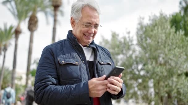 Homem Meia Idade Com Cabelos Grisalhos Usando Smartphone Sorrindo Parque — Vídeo de Stock