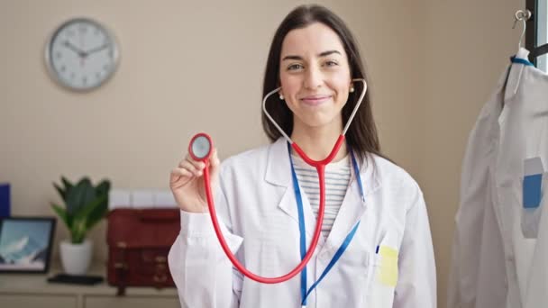 Νεαρή Όμορφη Ισπανόφωνη Γιατρός Χαμογελά Σίγουρος Κρατώντας Στηθοσκόπιο Στην Κλινική — Αρχείο Βίντεο